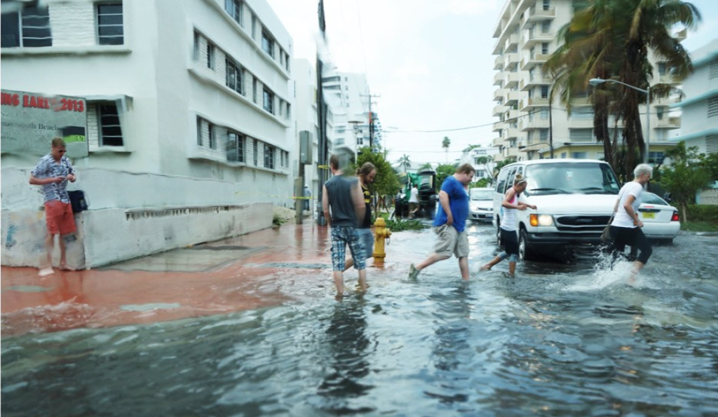 A photograph of people standing and running in flood waters in the US city of Miami, Florida.