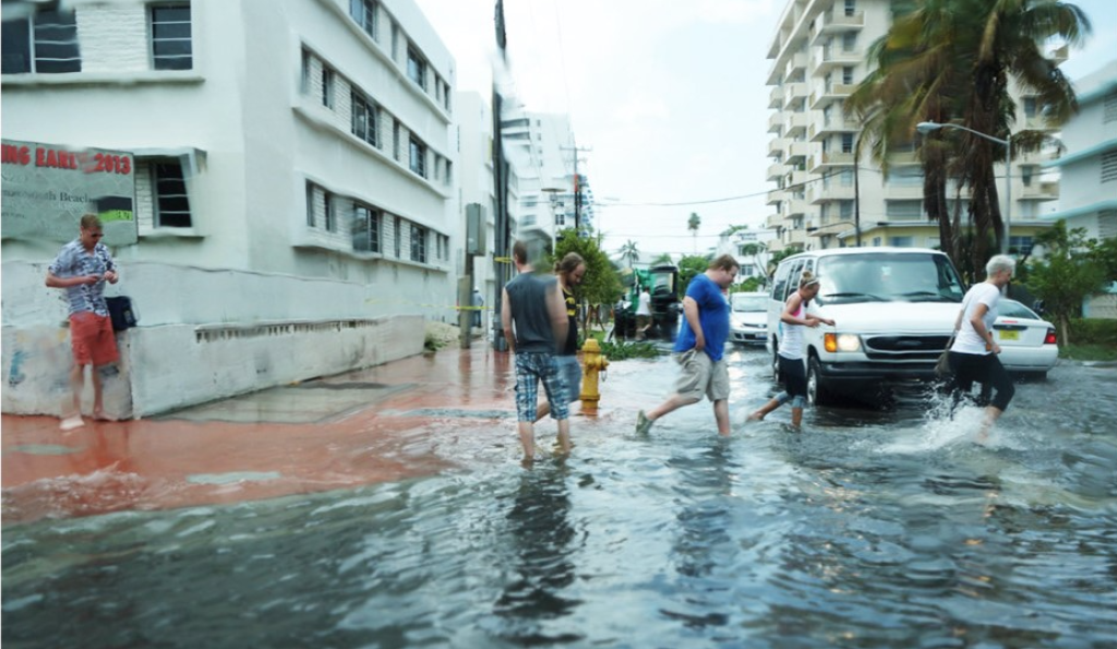 A photograph of people standing and running in flood waters in the US city of Miami, Florida. 