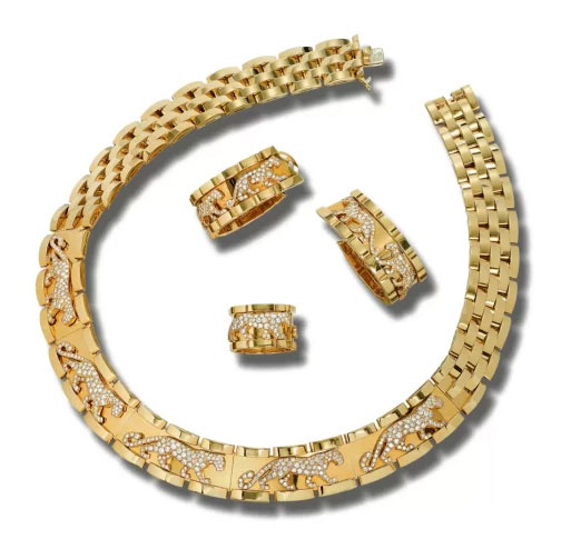 An auction image of a gold and diamond set of Cartier jewelry featuring decorative diamond panthers. Images includes a thick necklace, pair of earrings, and a ring.