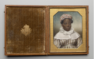 An open wooden frame by Sarah Goodbridge depicting a black woman on the right side in colonial dress framed with a gold octagonal cutout. The left side of the frame is all wood with a gold inlay of a flower and leaves. 