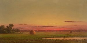 Landscape painting of a marsh at sunset painted by artist Martin Johnson Heade. The land is low and flat displaying green grasses. The sky is reddish brown and fades upwards to yellow green. Two haystacks glow in the sun.