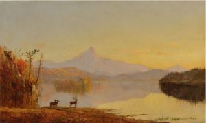 Image is of a landscape painting of a river scene and sunset. A pale mountain  sits in the distant. Two deer stand in the foreground at the edge of the water. Artwork is painted by artist Jasper Francis Cropsey.