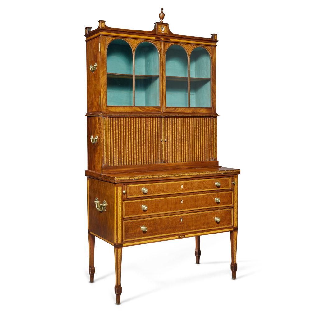 JOHN SEYMOUR/THOMAS SEYMOUR
The Garbisch Very Fine and Rare Federal Tambour Desk-and-Bookcase, c. 1800
Inlaid mahogany, satinwood, brass
84 1/2 x 37 1/2 x 19 3/8 in. 

ESTIMATE:
USD 80,000 – 120,000
ACHIEVED:
USD 177,800 (Premium)

Light brown tambour desk and bookcase.