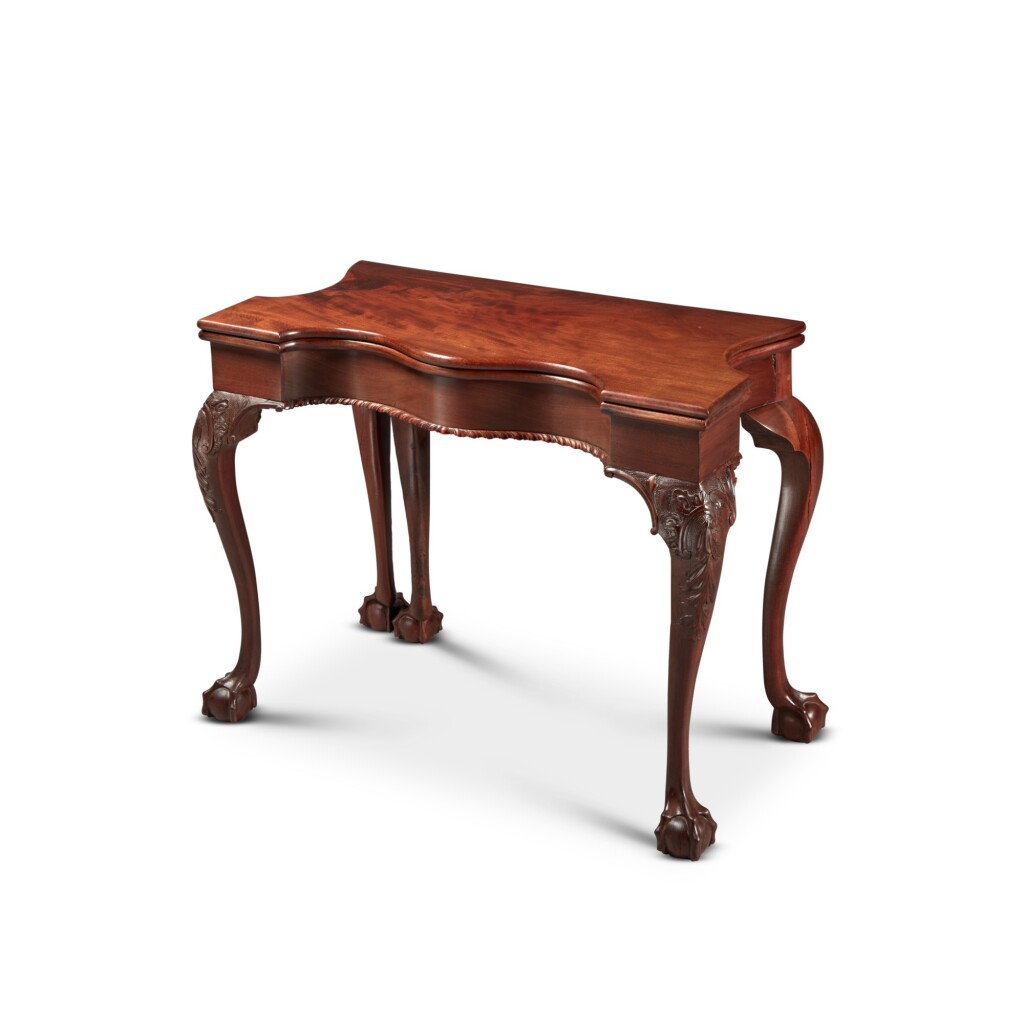An Important Chippendale Five-Legged Serpentine-Front Games Table, c. 1765
Carved and figured mahogany 
27 3/4 x 33 3/4 x 16 5/8 in.

ESTIMATE: 
USD 100,000 – 200,000
ACHIEVED: 
USD 279,400 (Premium)

Dark brown, five-legged table.